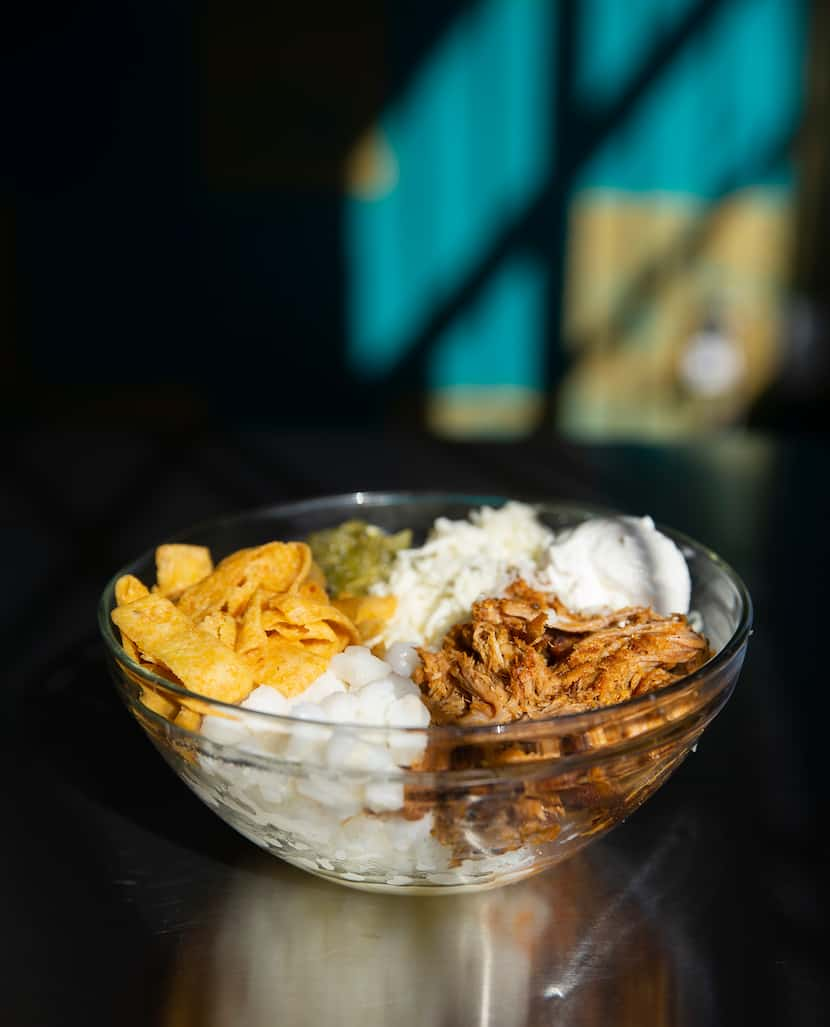 Pork pozole frito pie made with Hominy, asadero, salsa verde, corn chips and sour cream 