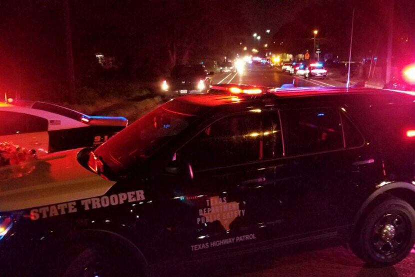 Dallas Police officers and Department of Public Safety troopers meet outside of a house on...