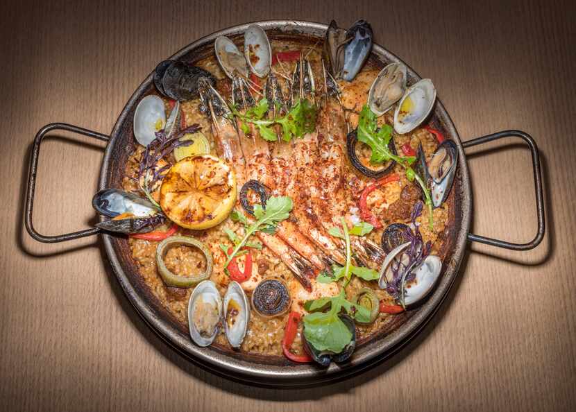 Paella Valenciana, a big pan of bomba rice is deeply flavored with shellfish stock, smoked...
