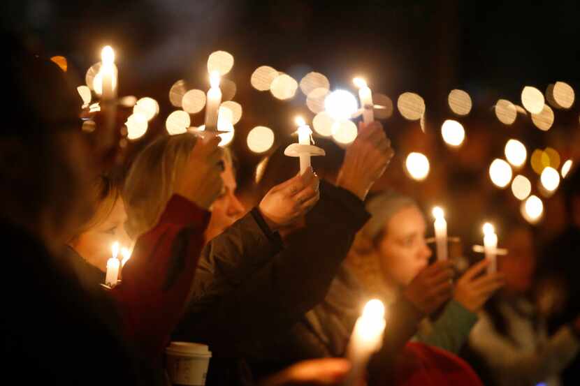 People hold up candles during a vigil for Detective Jerry Walker on Wednesday at Little Elm...