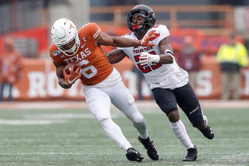 Devin Duvernay #6 of the Texas Longhorns attempts to avoid a tackle by Damarcus Fields #23...
