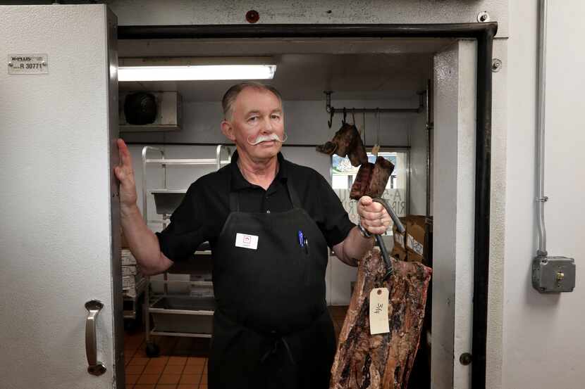 Gary Hirsch holds a slab of aged meat from the refrigerator at Hirsch's Specialty Meats in...
