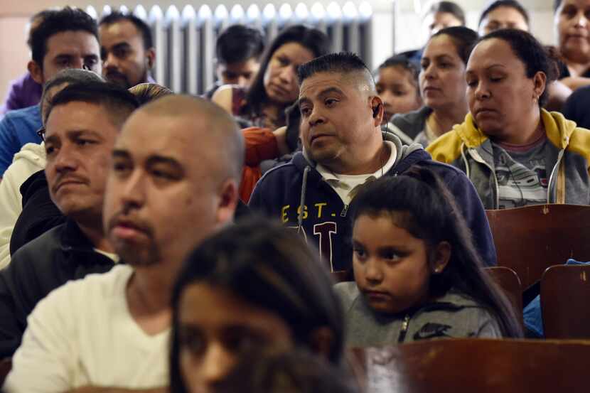 Los padres de familia observan atentos durante una audiencia sobre el cierre de la escuela...