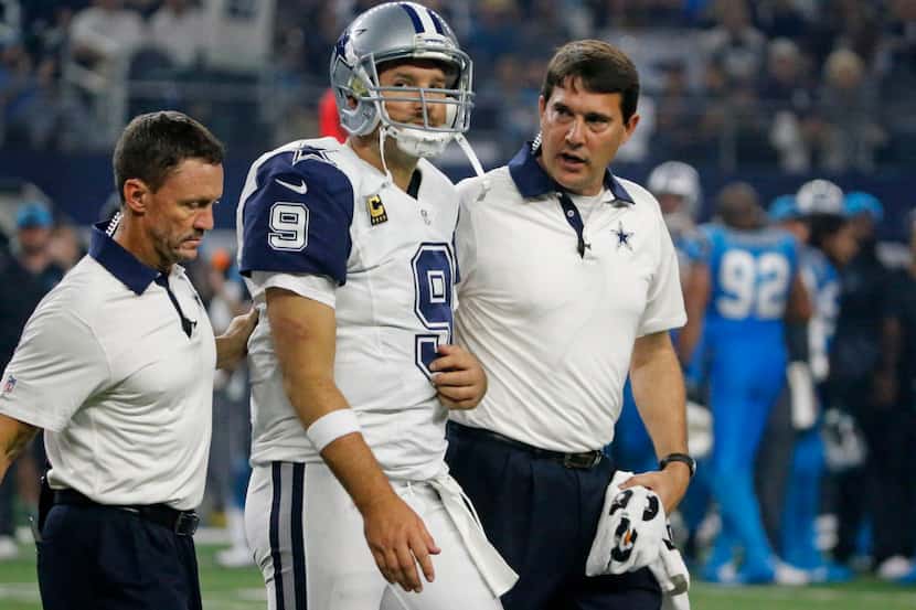 Dallas Cowboys quarterback Tony Romo (9) is helped off the field by trainers Britt Brown,...