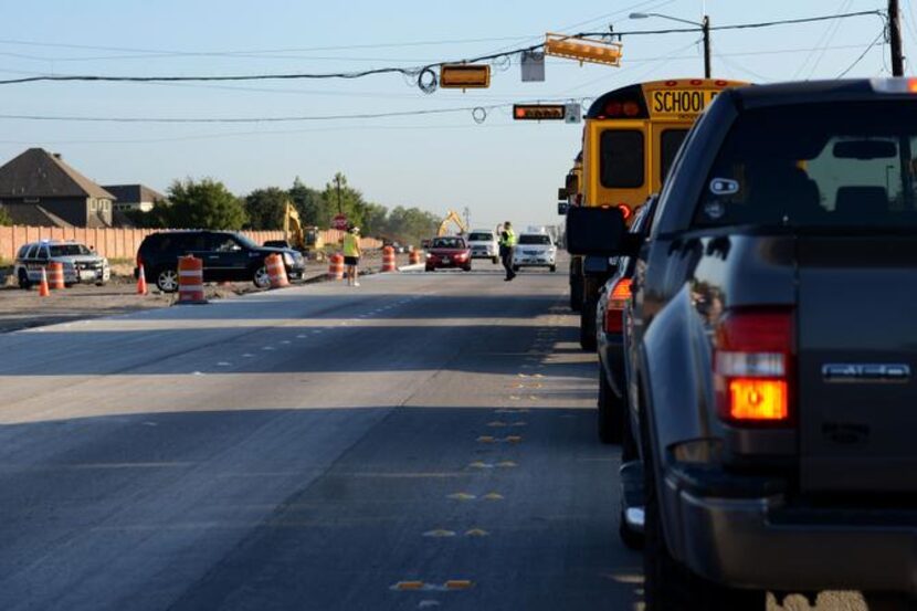 
A school bus and other vehicles wait as a police officer directs traffic along Murphy Road. 
