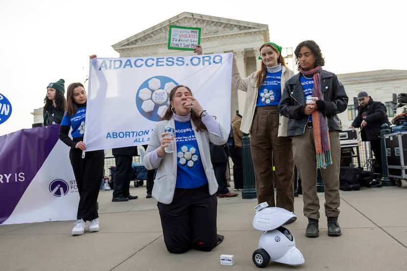 Mira Michels of Aid Access, takes a mifepristone pill in protest as demonstrators from both...