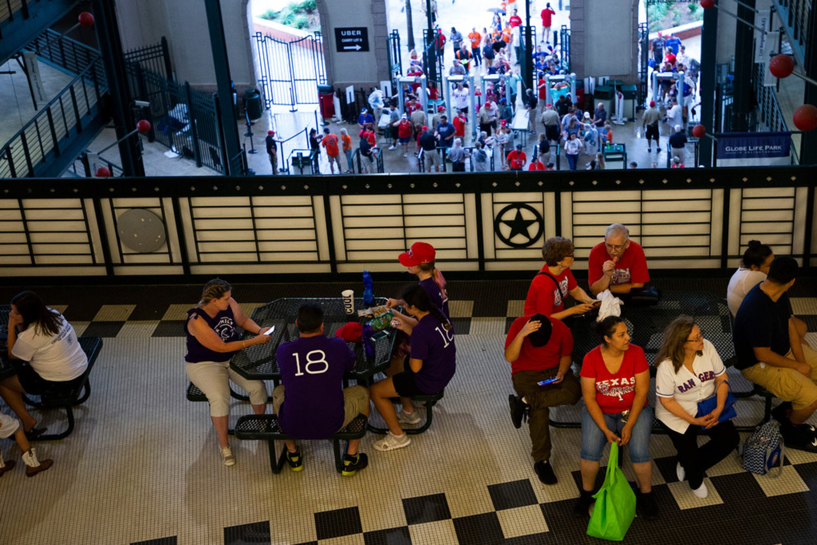 Fans take cover during a rain delay before a baseball game between the Texas Rangers and the...