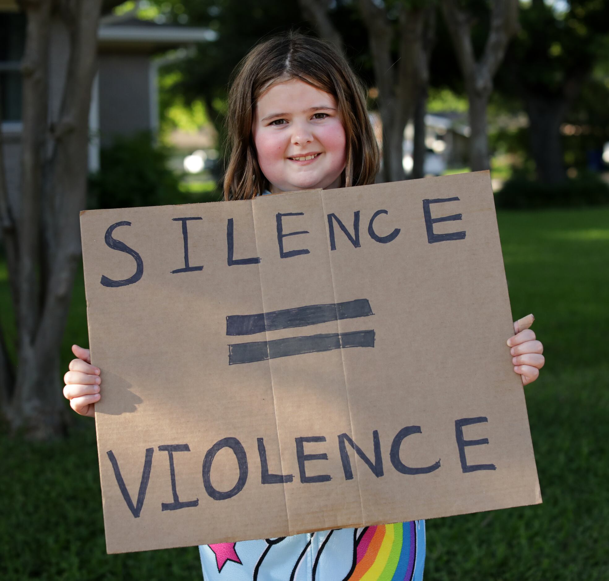 9-year-old Hannah Dodds holds a sign as protestors march from the historic town square back...