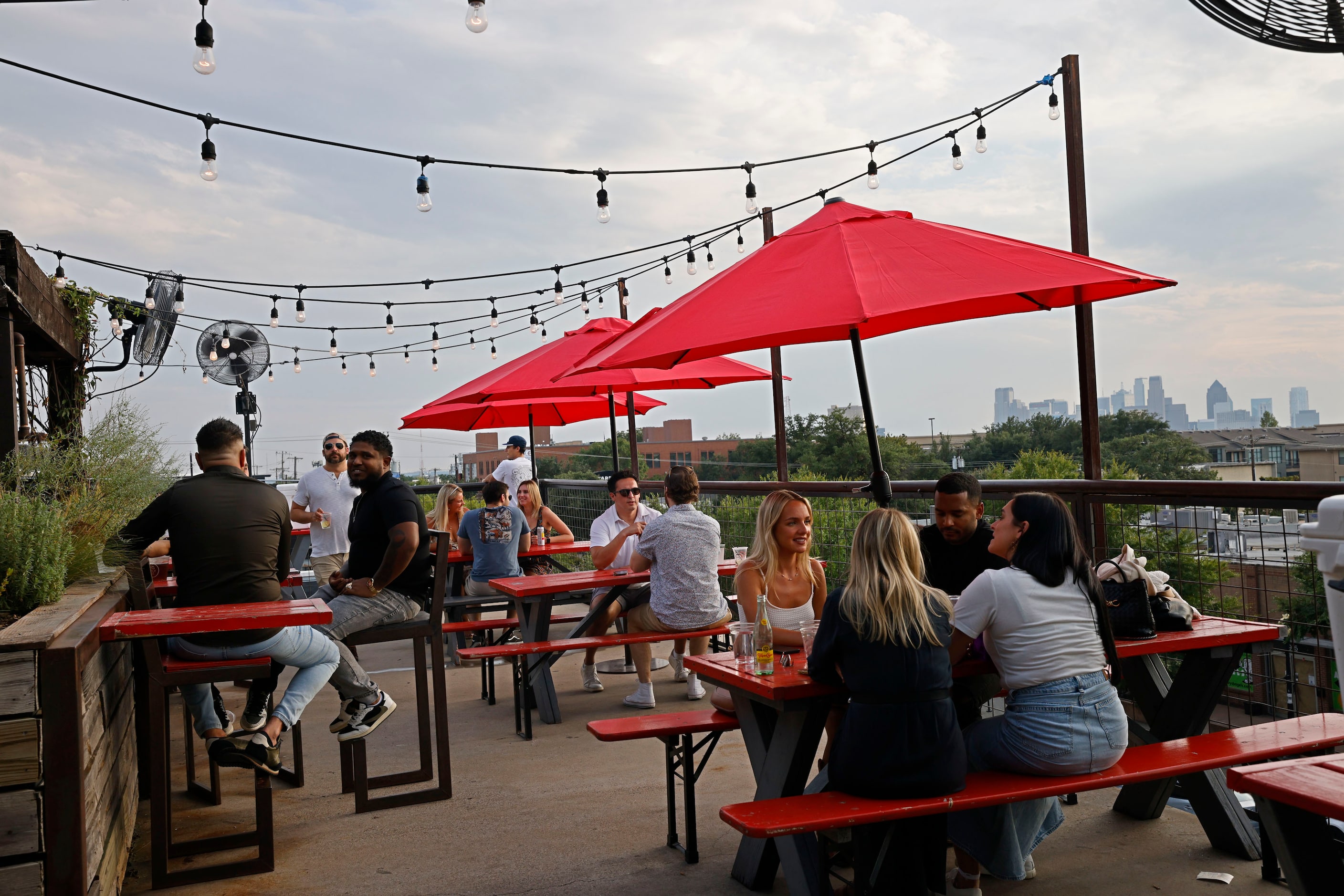 People sit on the patio at HG Sply Co. in the Lower Greenville neighborhood in Dallas,...