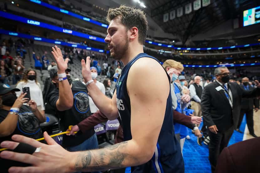 Dallas Mavericks guard Luka Doncic celebrates with fans as he leaves the court after scoring...