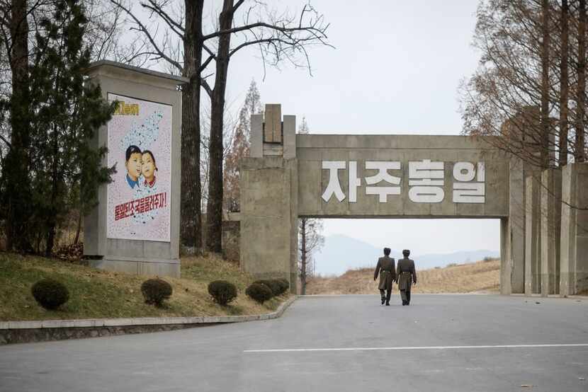 In this photo taken on November 30, 2016, North Korean soldiers walks past a propaganda...