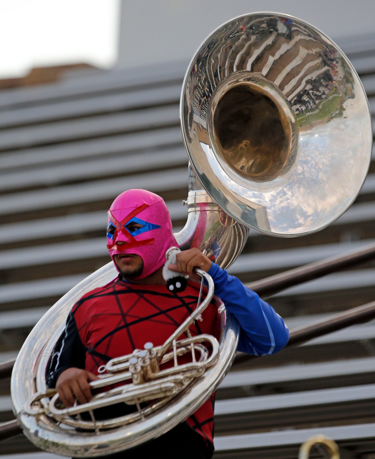 A masked South Garland High tuba player watches pregame workouts before the start of a high...