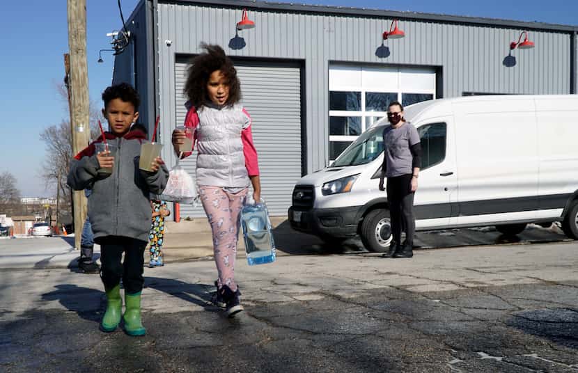 Michael Doamekpor (5) and his sister Kiera Doamekpor (9) carry drinks and filtered water to...