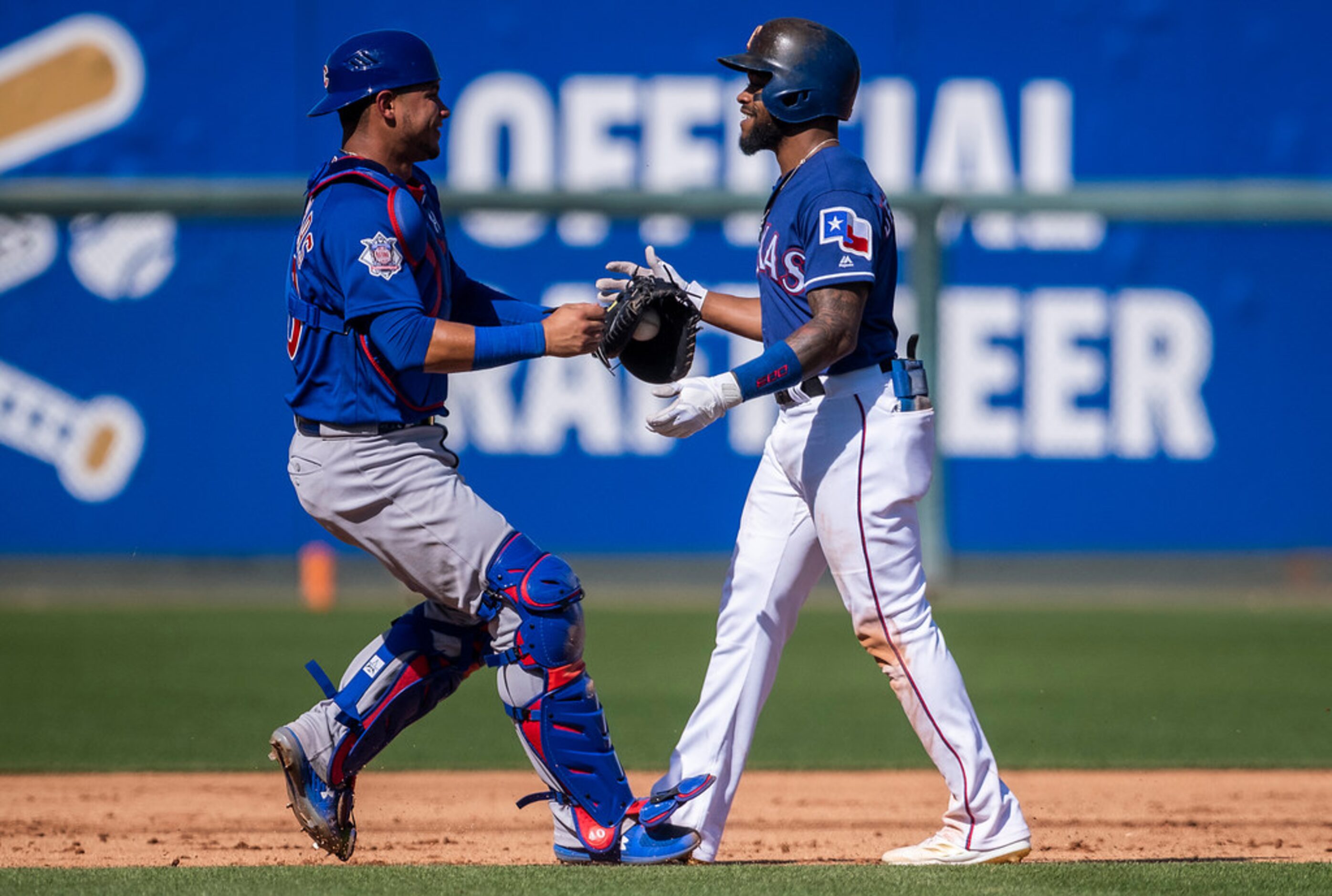 Texas Rangers outfielder Delino DeShields waits with a smile and a hug to be tagged out by...