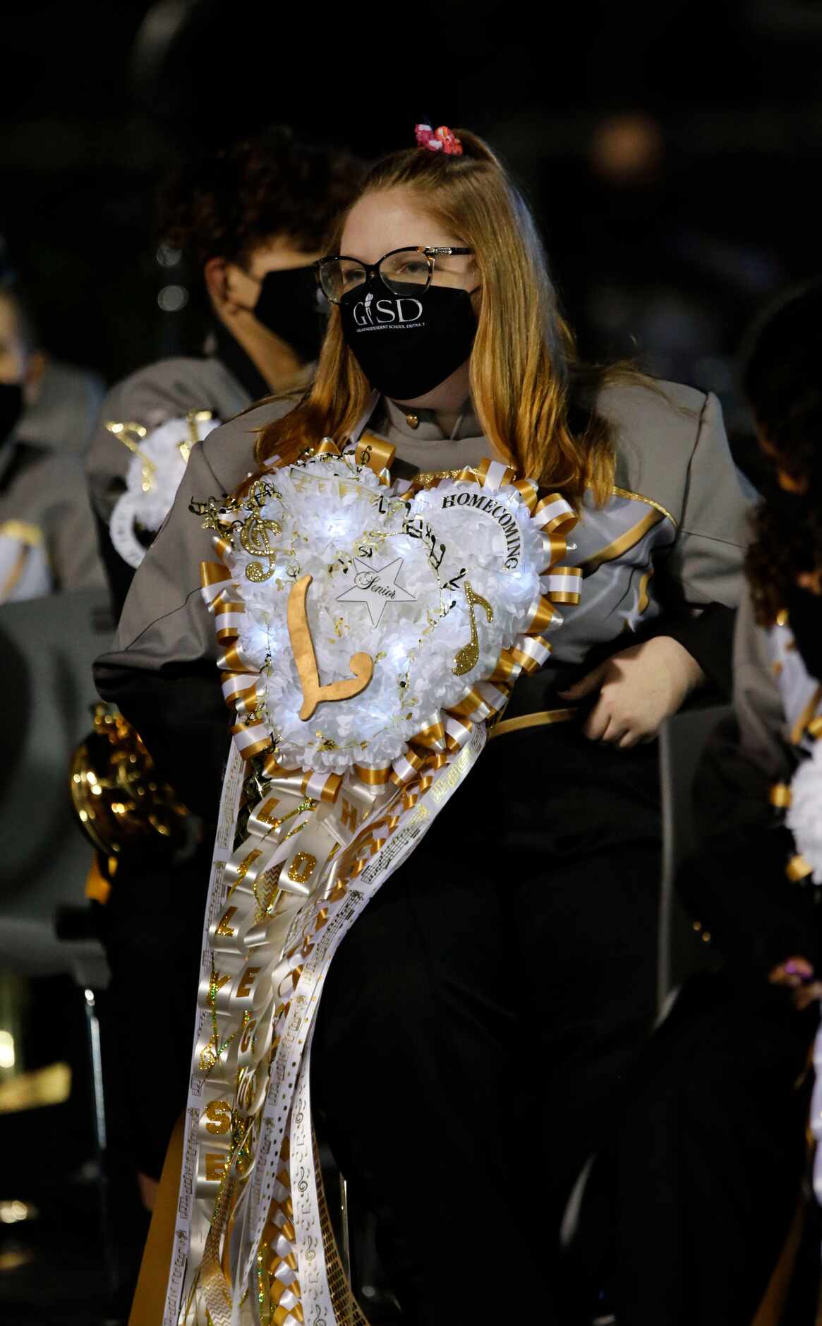 A Garland High band member and her electric-lit homecoming mum sit awaiting to perform...