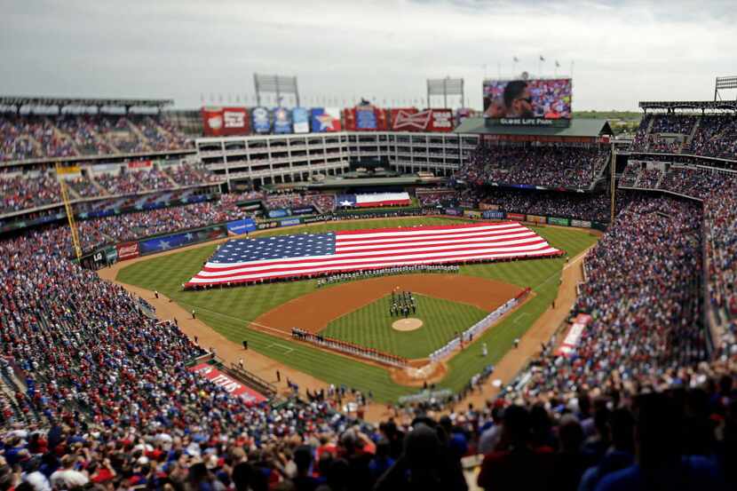 The American flag is unfurled on the field during the national anthem on Texas Rangers...