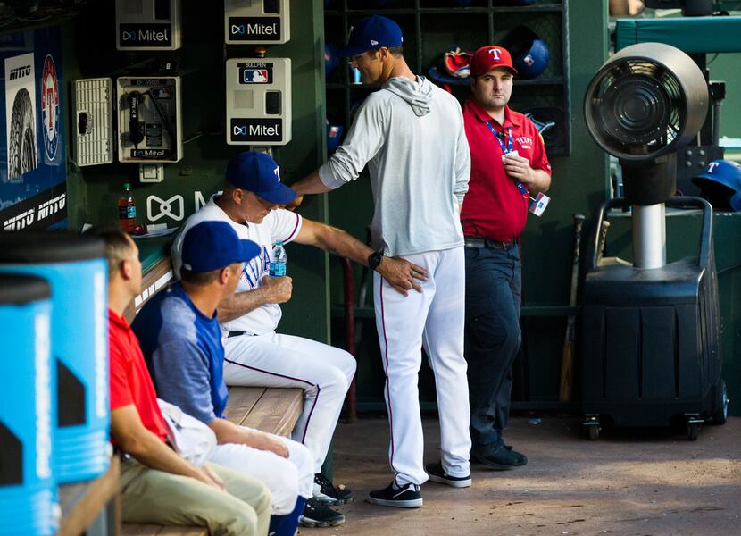 Texas Rangers pitcher Cole Hamels walks out of the Rangers' dugout, next to manager Jeff...