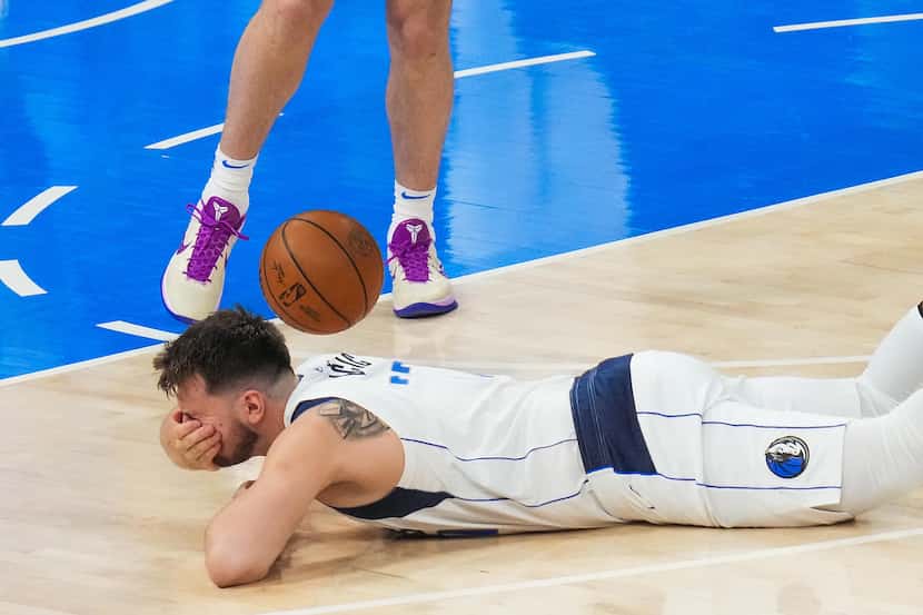 Dallas Mavericks guard Luka Doncic falls to the floor after being fouled during the first...