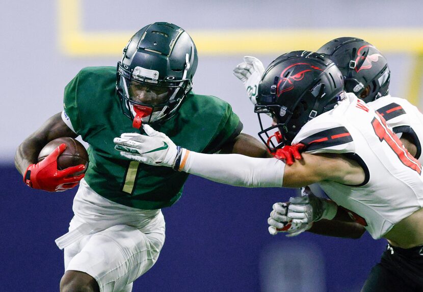 DeSoto’s Johntay Cook II (1) runs through a tackle from Rockwall-Heath’s Brady Luff (16)...