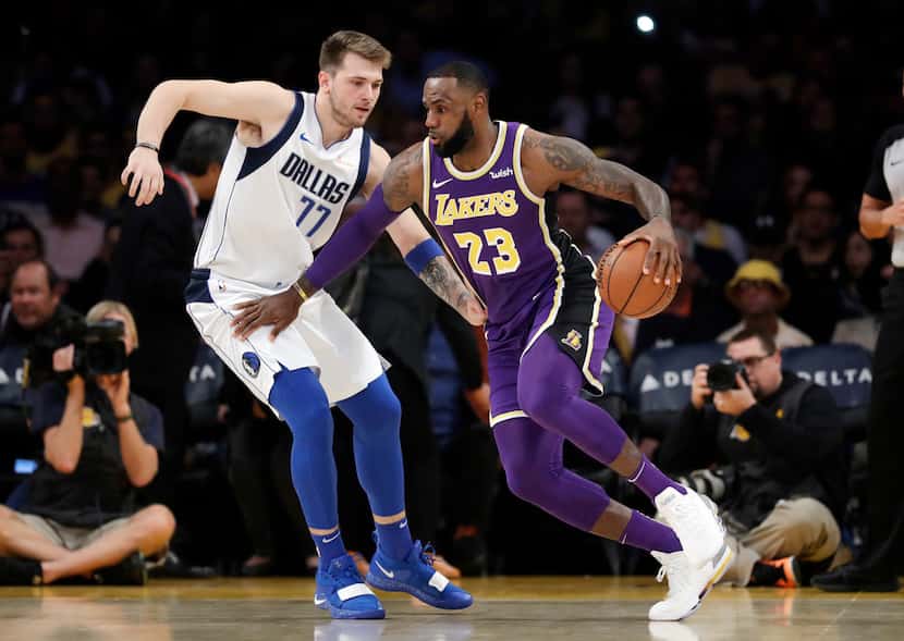 FILE - Lakers forward LeBron James (23) is defended by Mavericks guard Luka Doncic (77)...