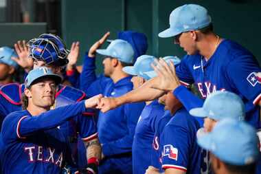 El pítcher de los Texas Rangers Jake Latz (de frente) saluda al jardinero Wyatt Langford...