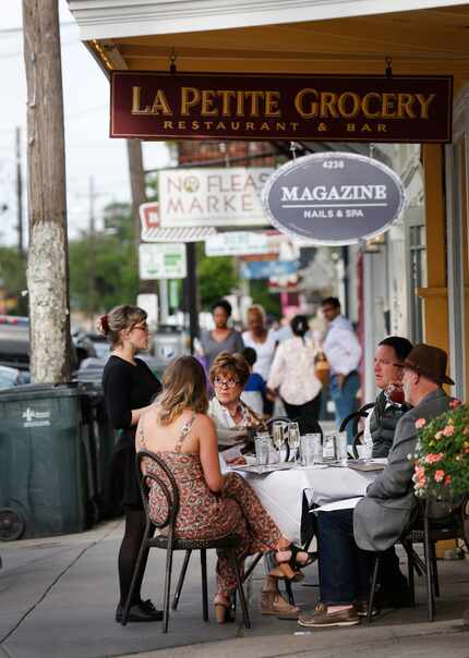 A waitress takes an order from a table outside La Petite Grocery on Magazine Street in the...