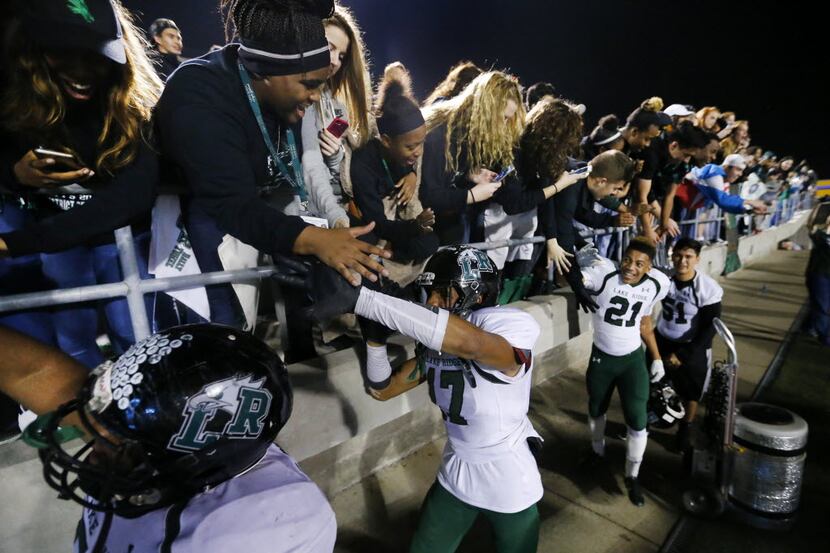 Mansfield Lake Ridge Bryson Jackson (17) and his teammates receive high-fives from fans...