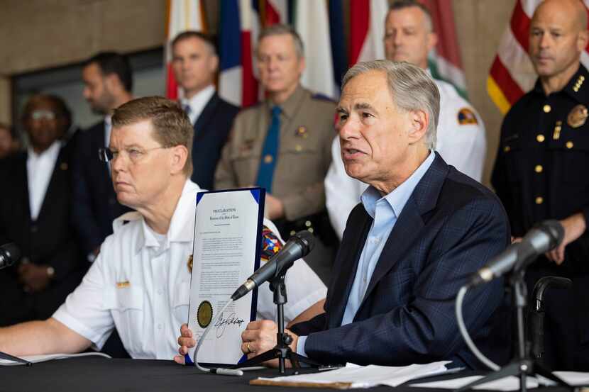 Gov. Greg Abbott holds up a disaster declaration for 23 counties impacted by severe flooding...