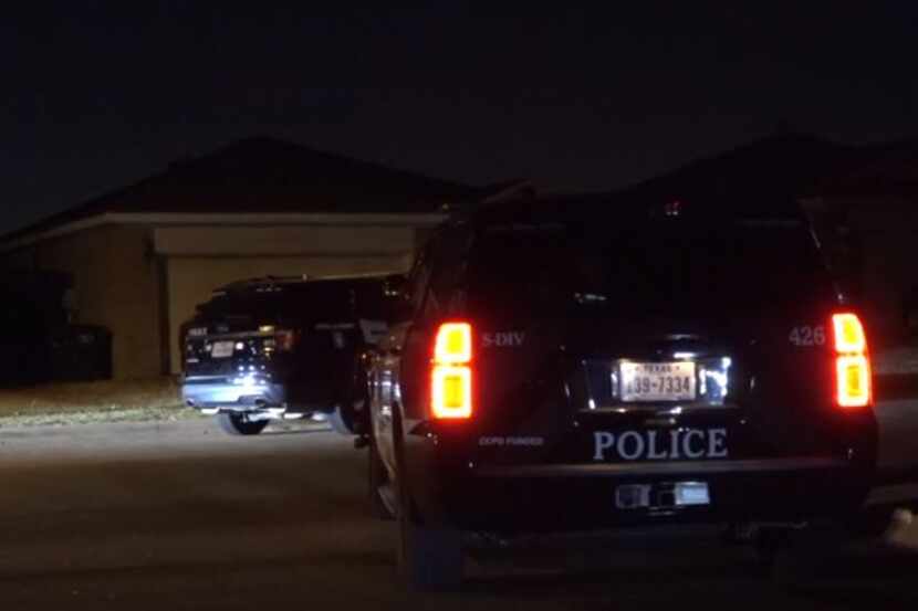 Police vehicles sit outside a home in Fort Worth near where shooting broke out between a...