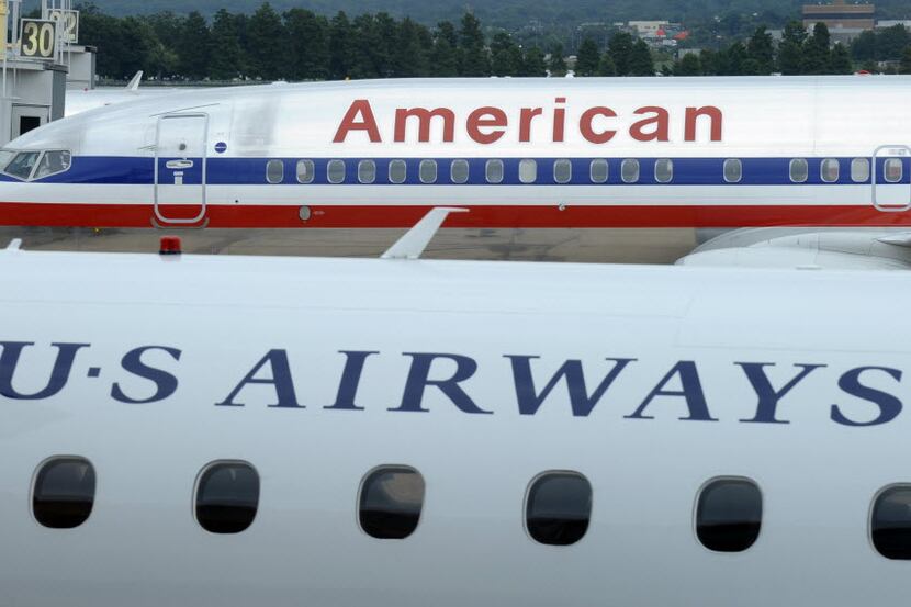  An American Airlines plane is parked behind a US Airways plane. The US Airways brand...