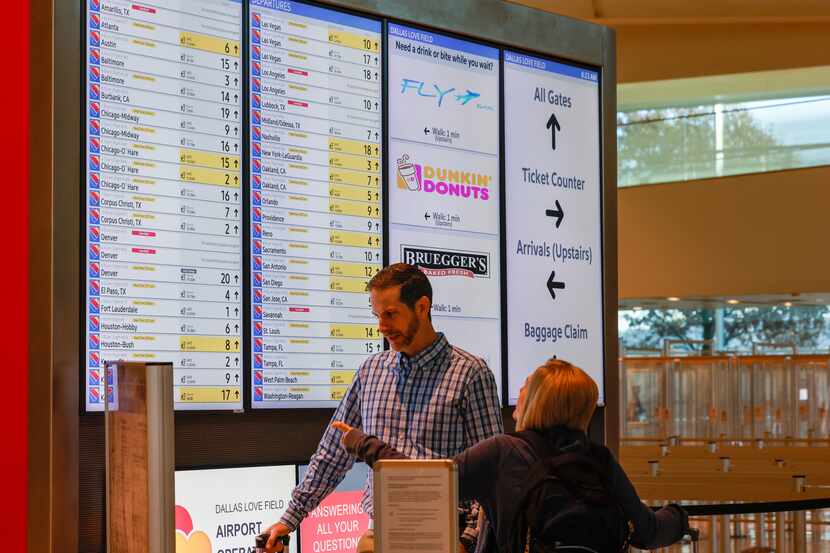 Chris Knollmeyer (left) and Patti Crisp stop to look at a departure board for their flight...