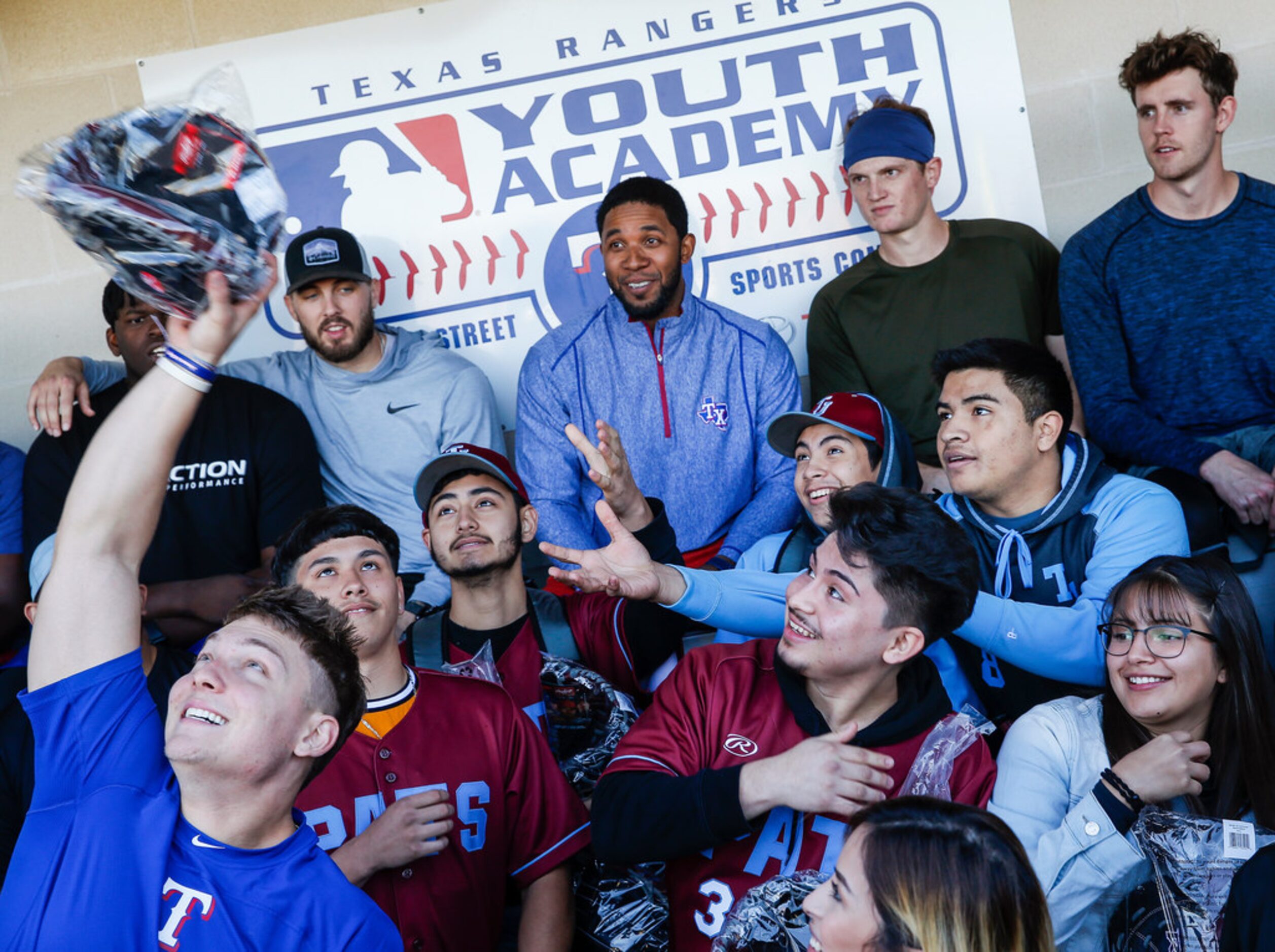 Thomas Jefferson High School baseball players reach to catch new gear donated by Rangers...