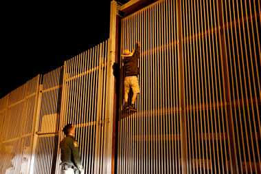 Border Patrol agent Eduardo Olmos apprehends a Mexican immigrant trying to climb the...