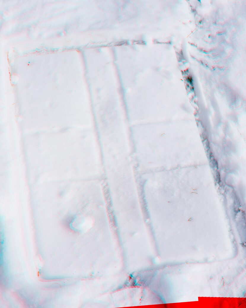 A snow shower outlines a utility box on the ground.