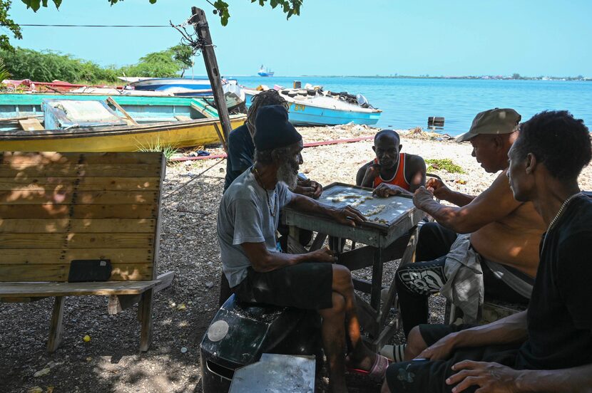 Pescadores juegan al dominó después de sacar sus barcos del agua para protegerlos del...