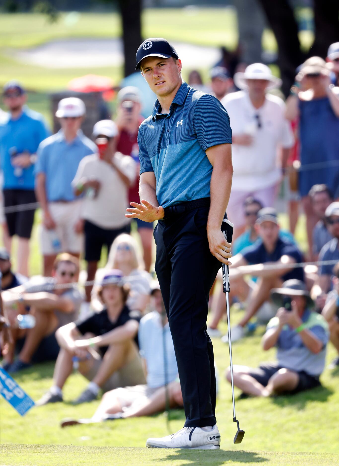 Professional golfer Jordan Spieth motions his ball to slow as he putts from the fringe on...