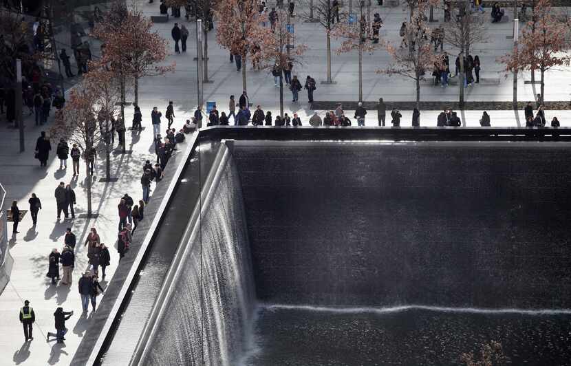 Visitors to the National September 11 Memorial and Museum circle one of two reflecting...