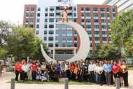 Large group of students pose in front of a crescent moon shaped sculputure outside State...