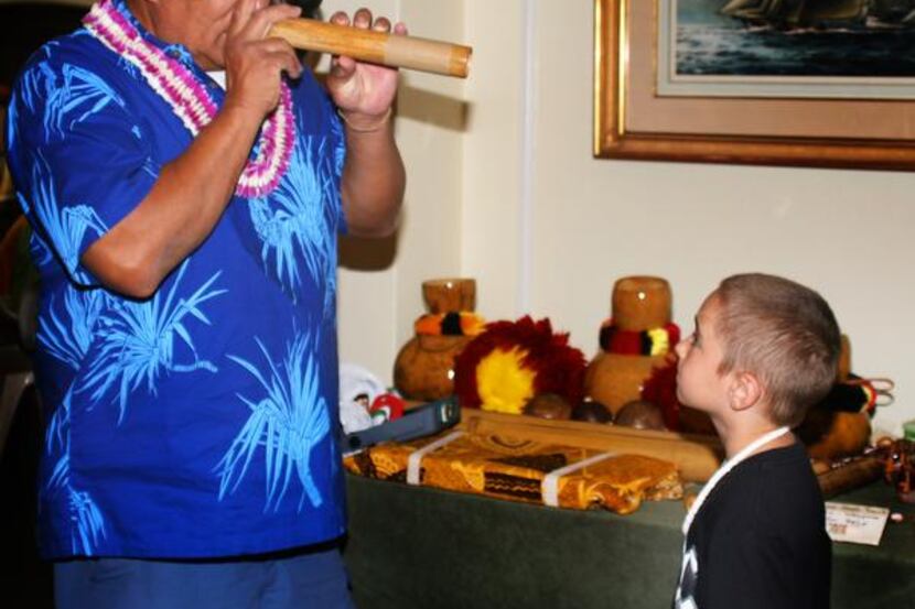 
A native Hawaiian’s nose flute performance fascinates a visiting boy.

