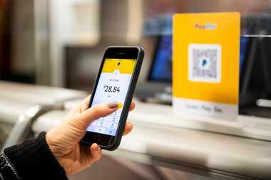 A woman holds her phone up to scan a QR code for a touch-free form of payment.