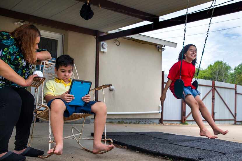 Maria Tobias (left) helps her 8-year-old son, Javier Garcia (center), during a reading...
