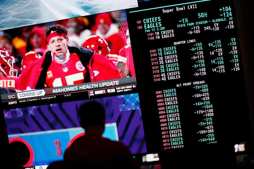 A person gambles as betting odds for NFL football's Super Bowl are displayed on monitors at...