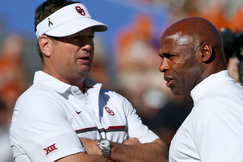 Oklahoma head coach Bob Stoops, left, and Texas head coach Charlie Strong, right, talk...