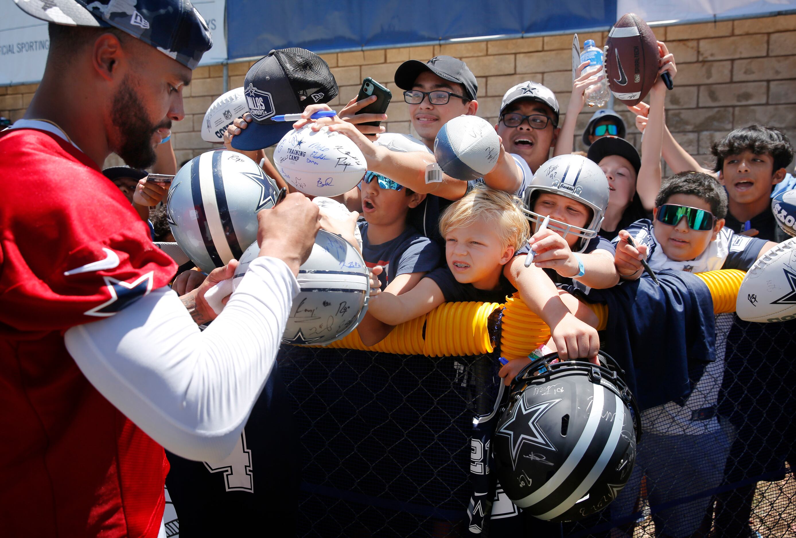 Young fans squeeze through the crowd in hopes of getting an autograph from Dallas Cowboys...