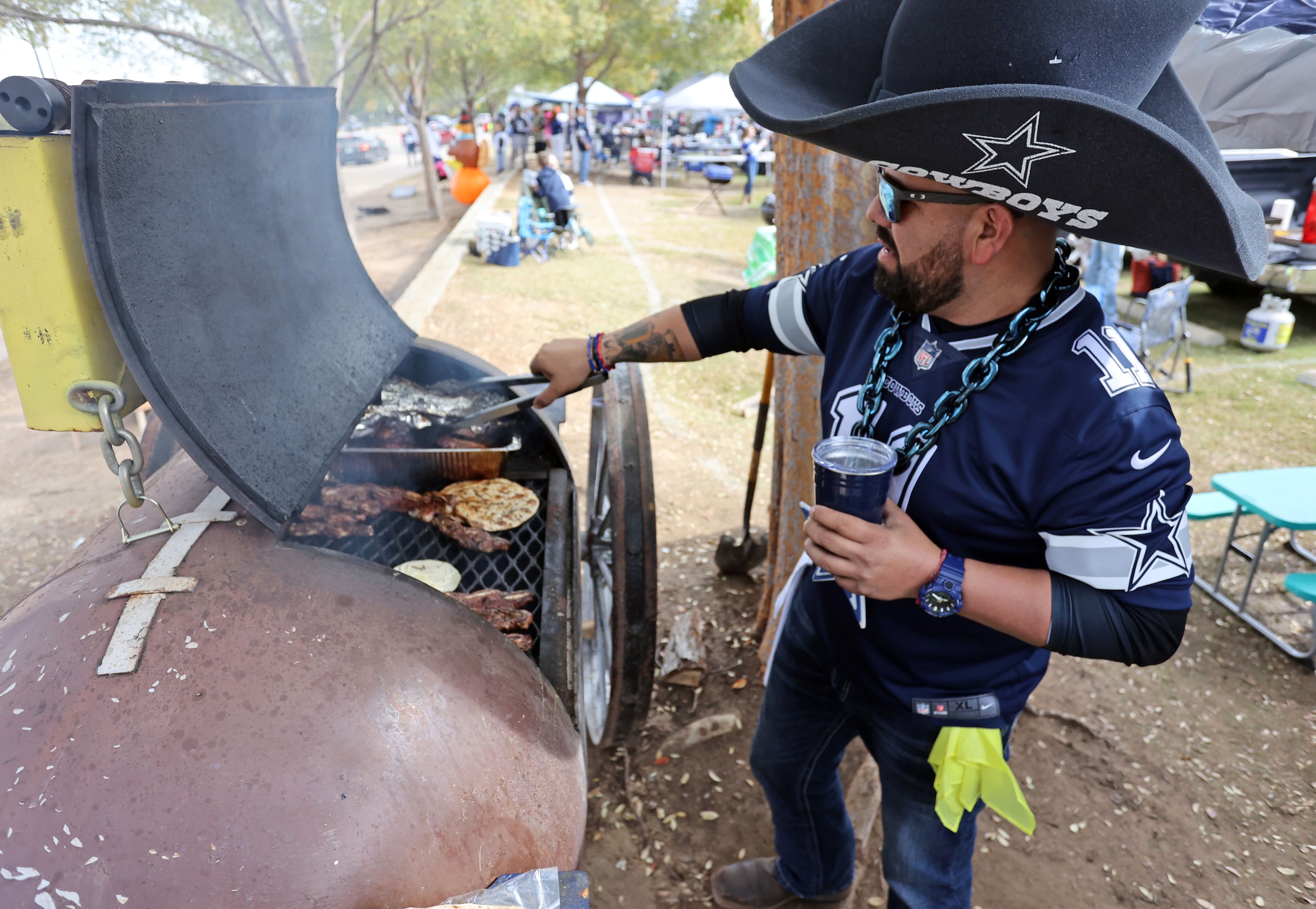 Jaime Castanela, of Corpus Christi, TX, mans a grill, while tailgating before a NFL football...