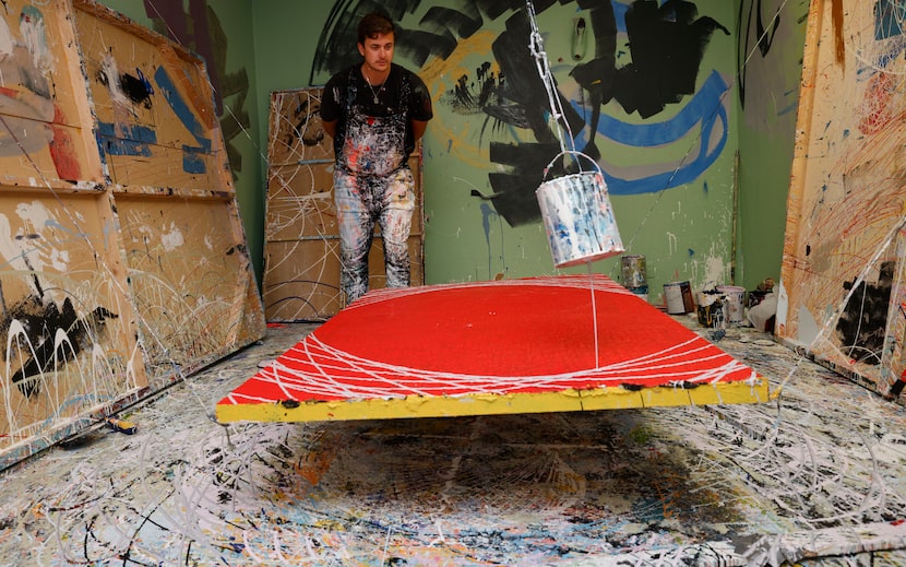 Action painter Cole Newman carefully watches a paint can make lines on a canvas. 