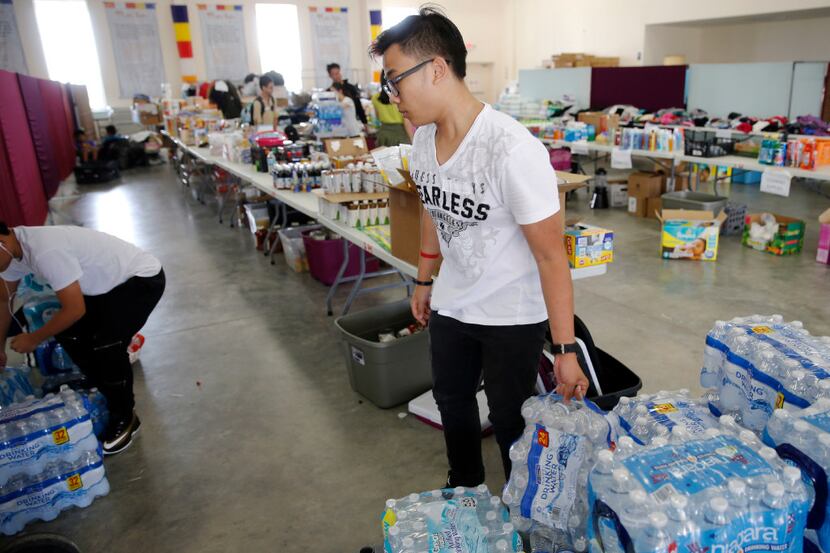 Huy Huynh works on stocking cases of water in a donation area for hurricane Harvey victims...