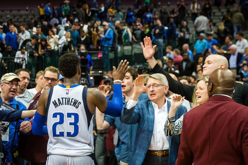 Dallas Mavericks guard Wesley Matthews celebrates with fans as he leaves the court after a...