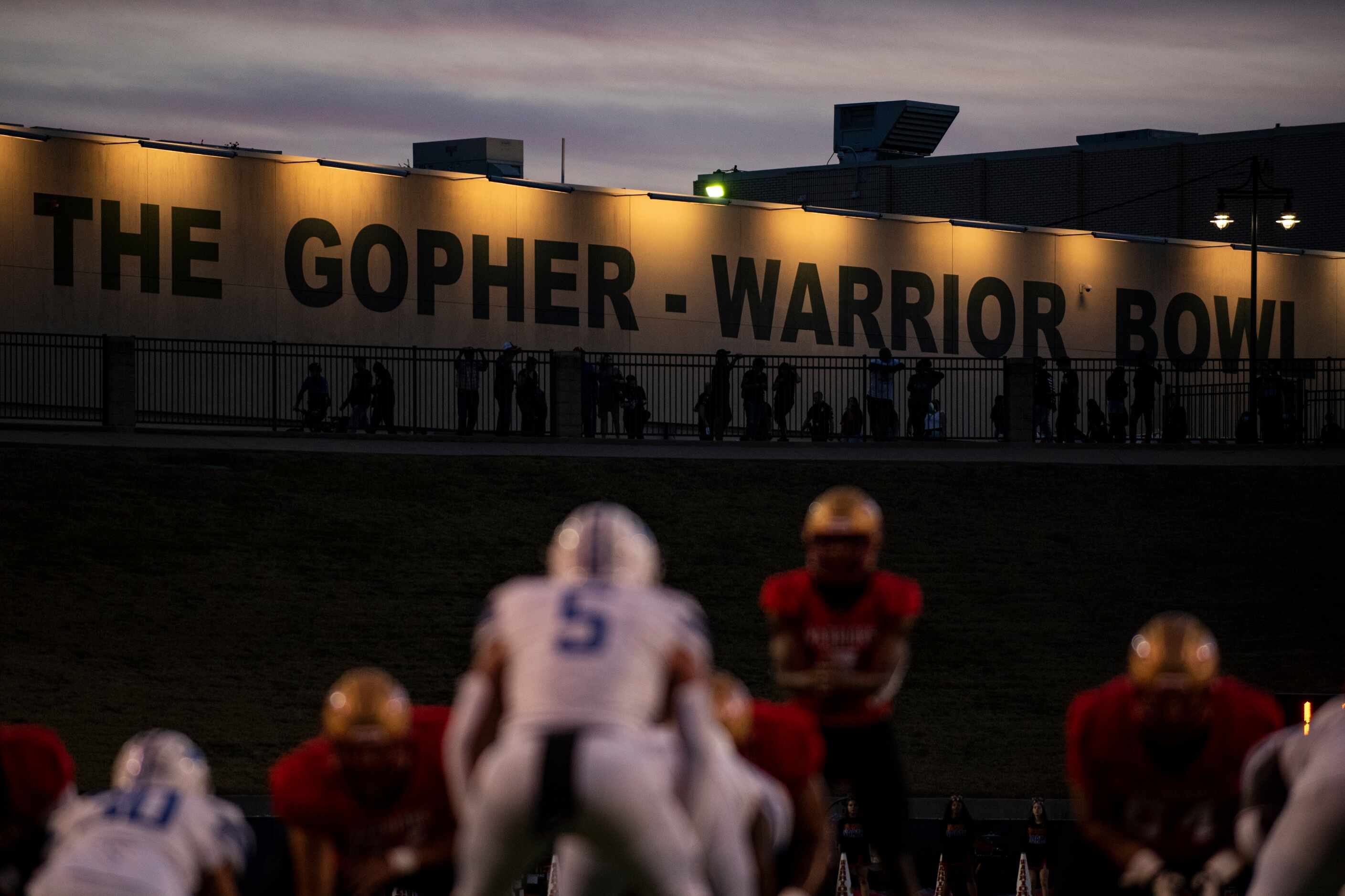 The Gopher-Warrior Bowl wording is illuminated by lights as the sun sets during South Grand...