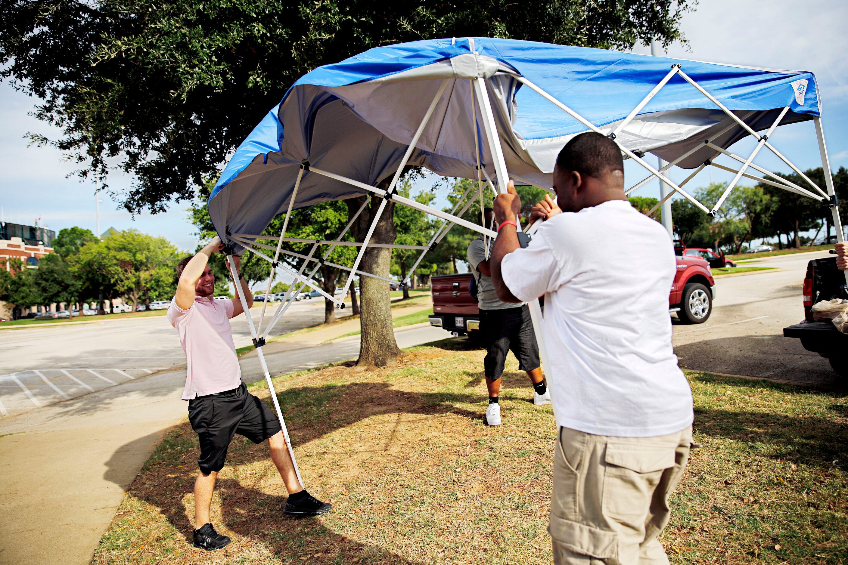 Corey Haynes (left) tries to help fans set up a tent in the wind before the Dallas Cowboys...